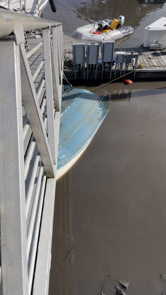 Capsized boat wedged under a pedestrian bridge